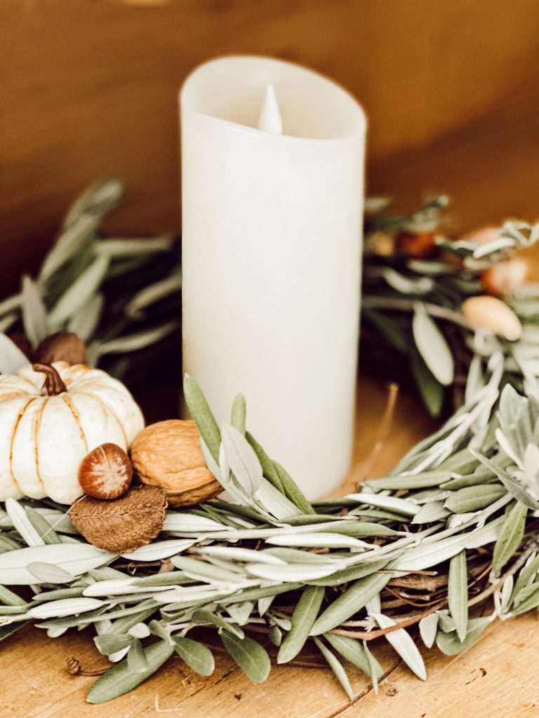 DIY candle ring with grapevine wreath on a scrubbed pine hutch and a pillar candle in the center.