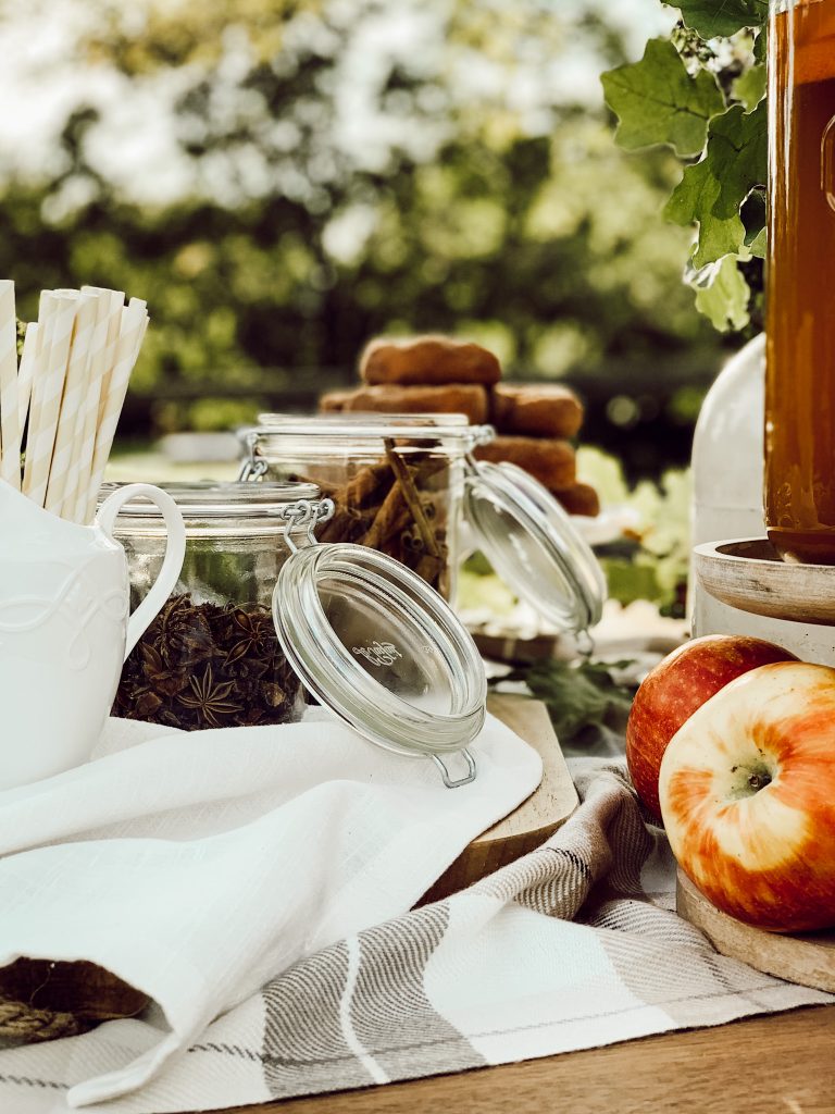 DIY fall drink station with fresh apple cider and jars of spices.