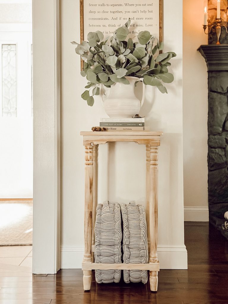 Fall arrangement of silver dollar eucalyptus in an urn on a side table.