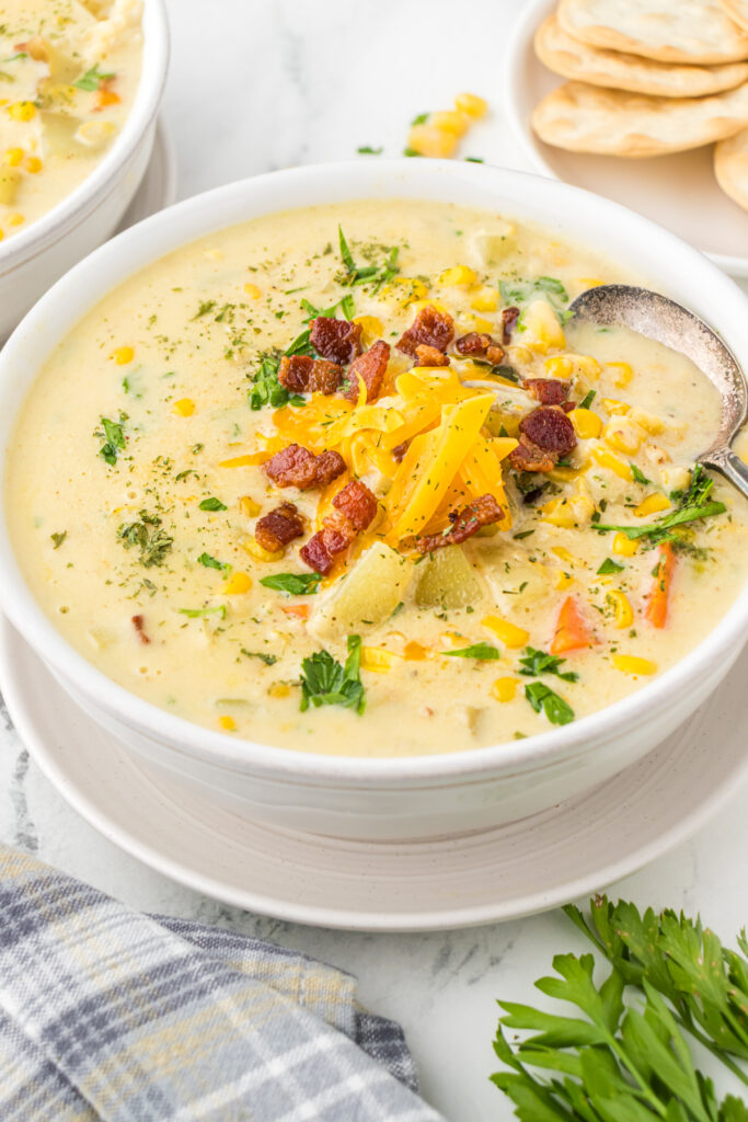 A bowl of hearty corn chowder with crackers on the side.