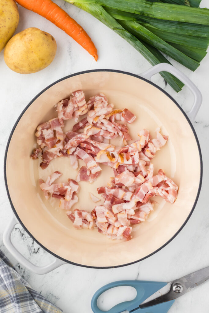 Cut the bacon strips into small pieces and add to a large dutch oven.