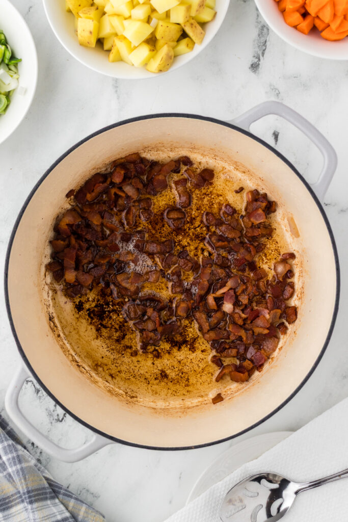 Cooking the chopped bacon in a dutch oven over medium-high heat to create the flavorful base of the chowder.