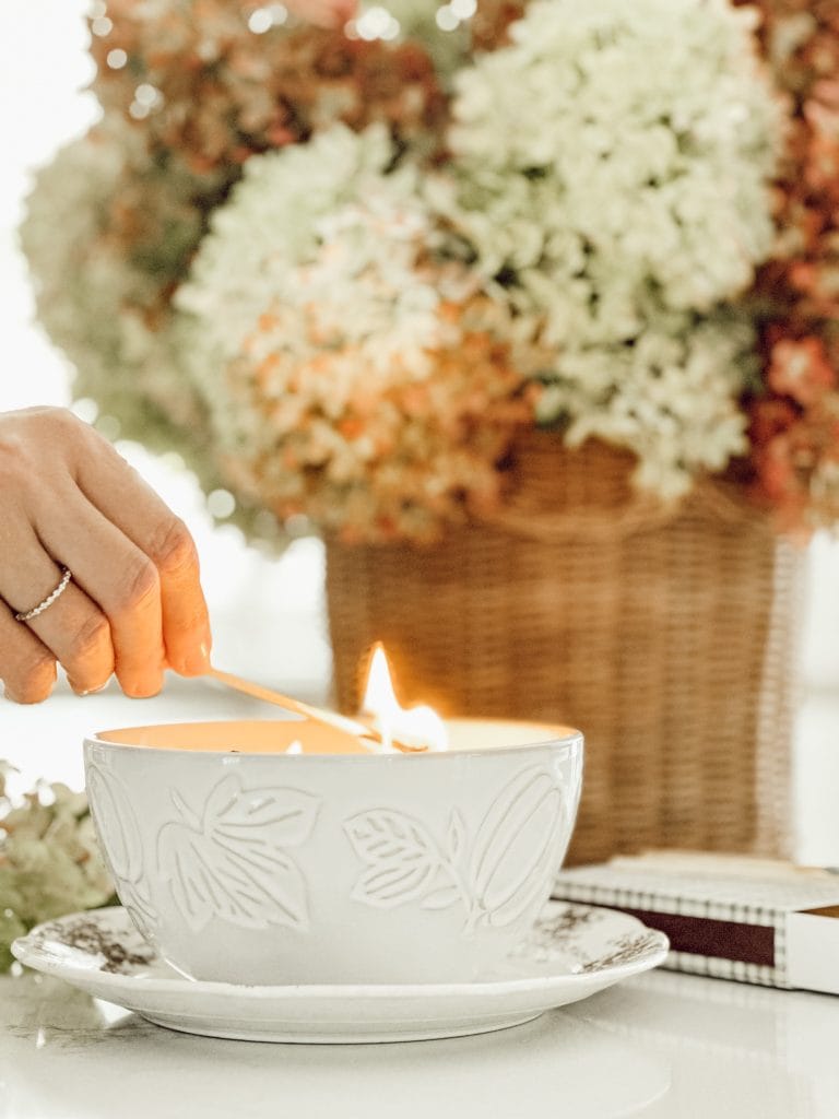Lighting a candle to show you how to decorate for fall using your five senses for the ultimate cozy home.