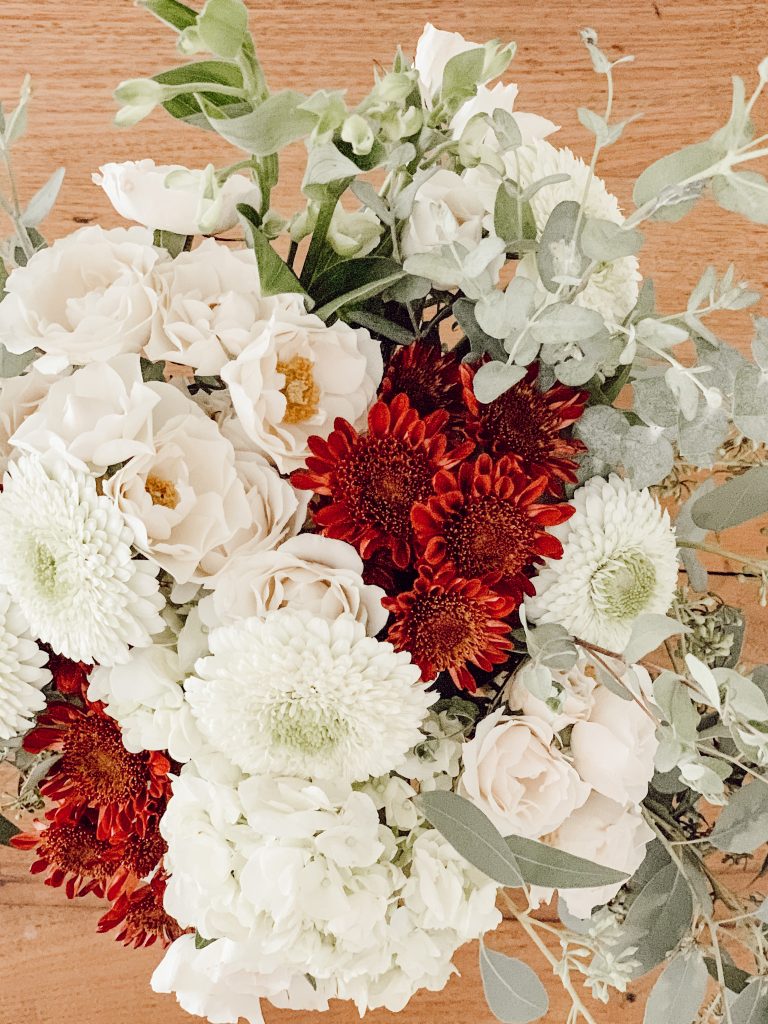 White roses, red mums, white dahlias, and eucalyptus to create a flower bouquet for your fall decorations.
