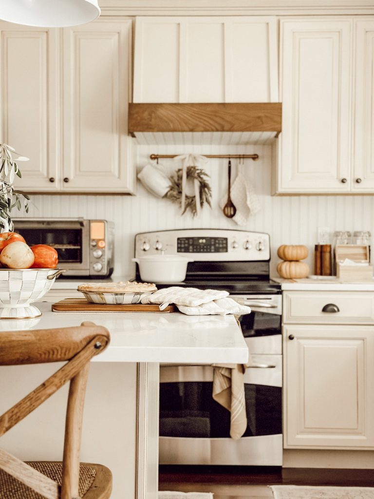 Free fall decor ideas in the kitchen with an apple pie on the kitchen counter and bowl of apples.