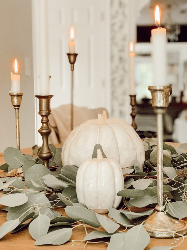 Fresh eucalyptus, pumpkins, and candles on a fall tablescape for the autumn season.