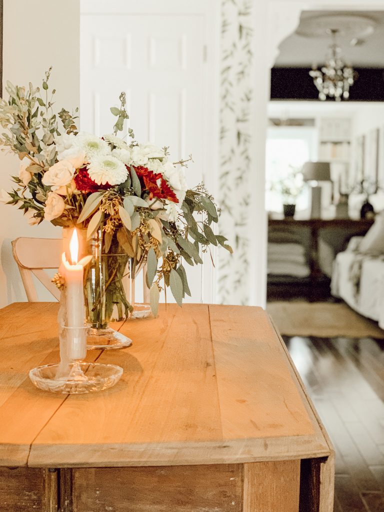 Fresh fall flowers and eucalyptus in a fall arrangement in a glass vase on the kitchen table.