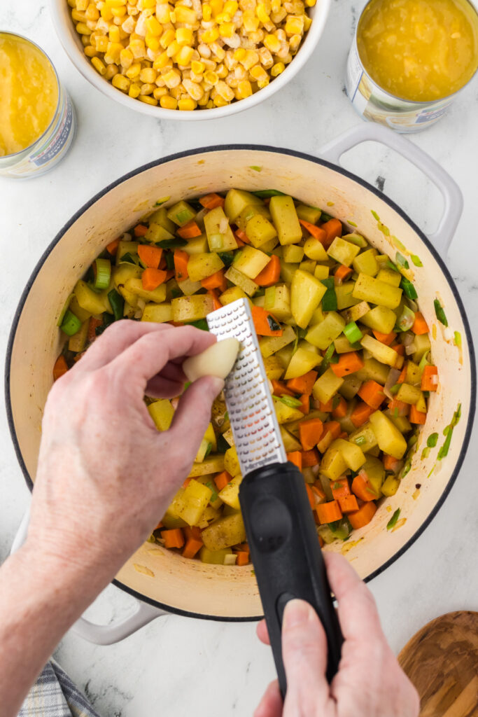 Grating in a garlic clove to the corn chowder base for more depth of flavor.