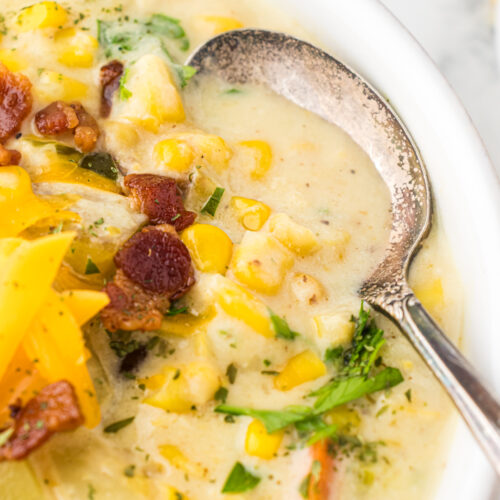 Bowl of hearty, creamy corn chowder featuring fresh corn, yukon gold potatoes, carrots, leeks, bacon, and fresh parsley.