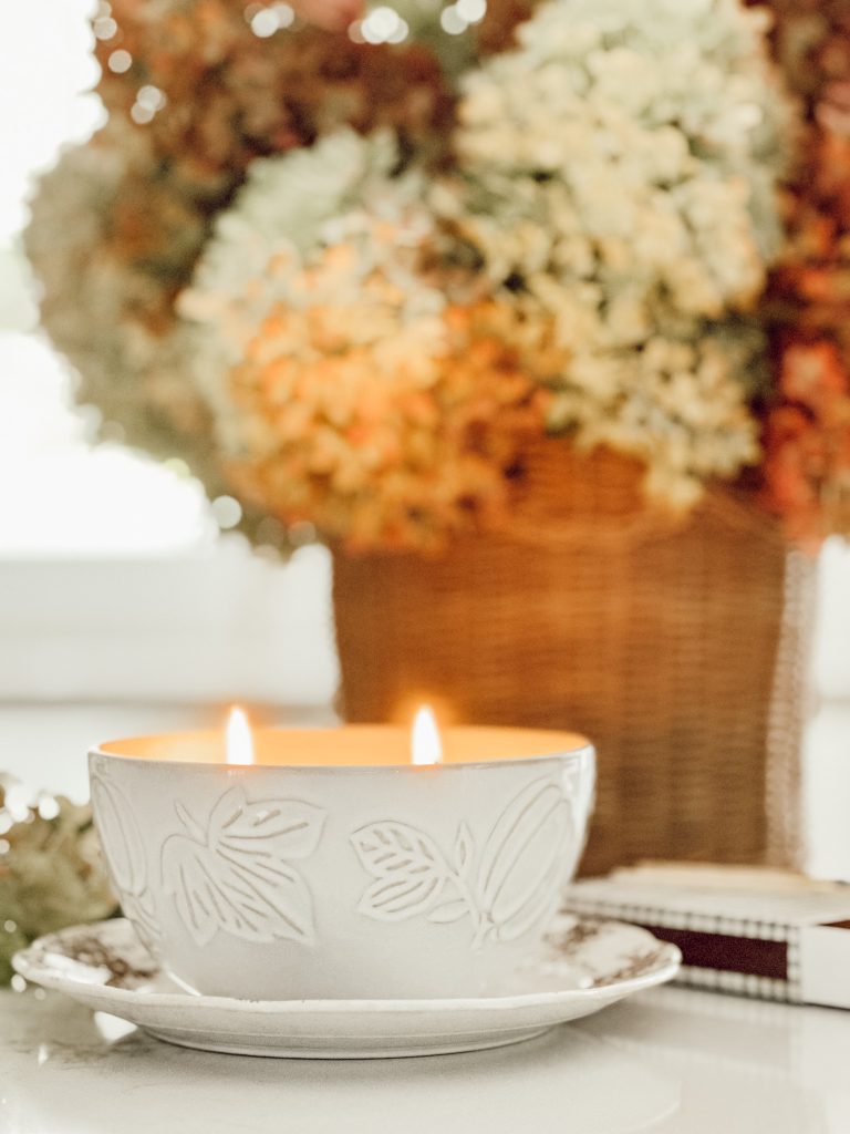 Home decor using your five senses to decorate with a lit candle and a basket of dried florals. 