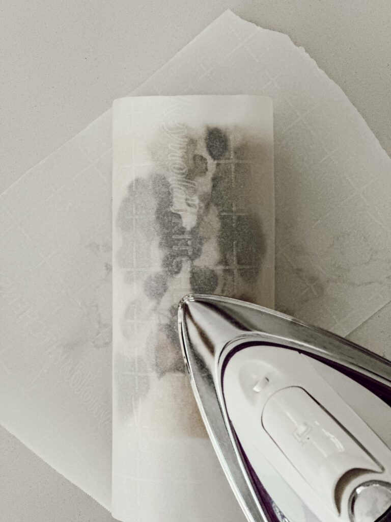 Place a piece of wax paper over the candle and napkin, then use an iron to apply heat to adhere the napkin to the pillar candle.