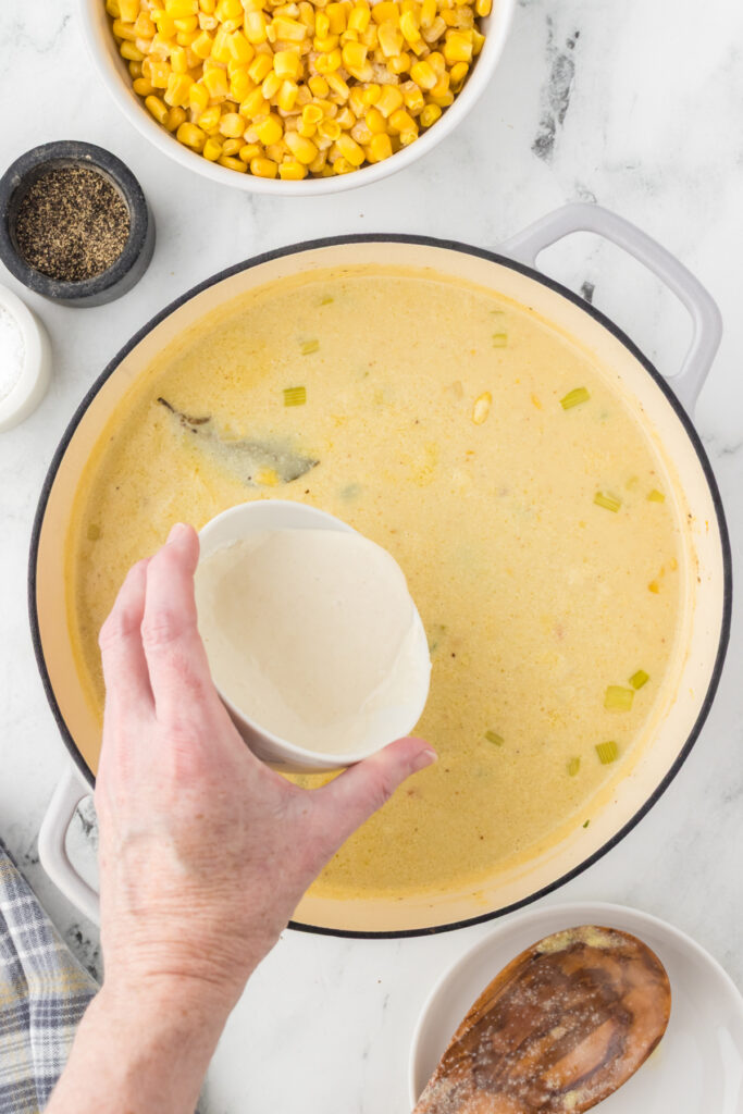 Pouring the slurry made with cornstarch and water into the chowder base to thicken the soup.