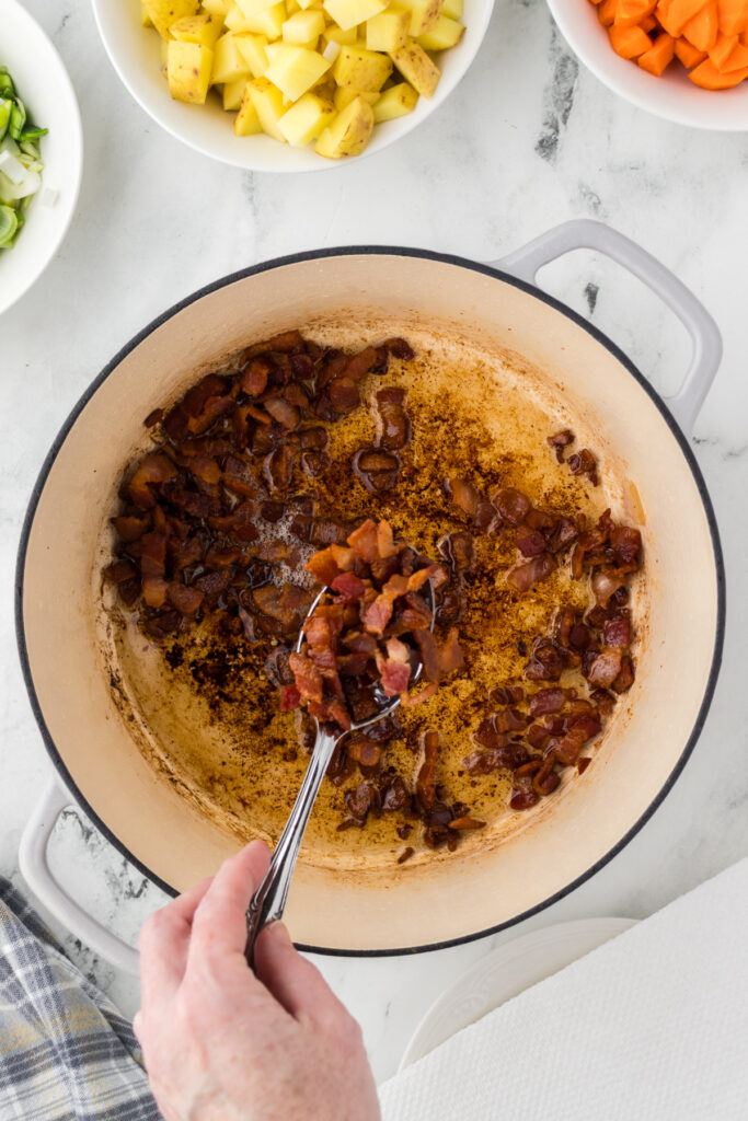 Remove the cooked bacon bits from the dutch oven with a slotted spoon to leave the bacon grease in the soup pot.