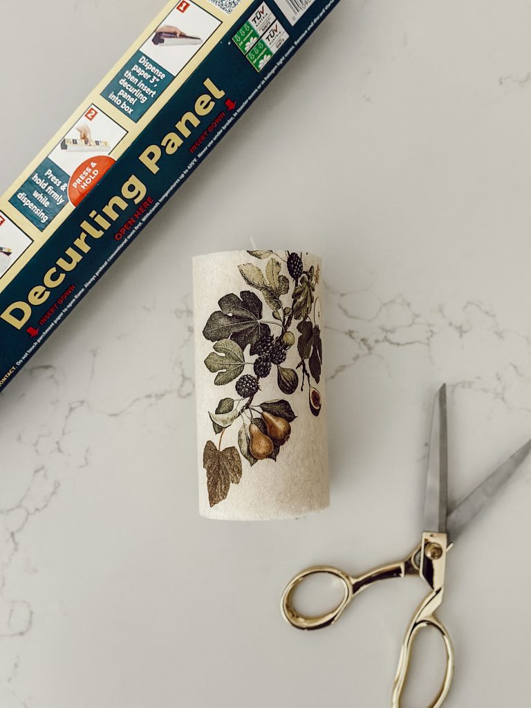 The simple supplies to adhere the napkin to the candle include scissors, parchment paper, and an iron.