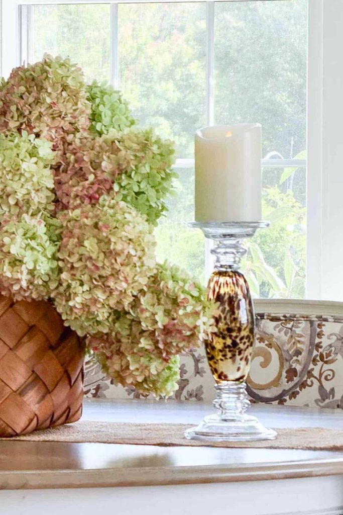 Weekly Wednesday Wish List StoneGable blog with a basket of hydrangeas and a pillar candle.