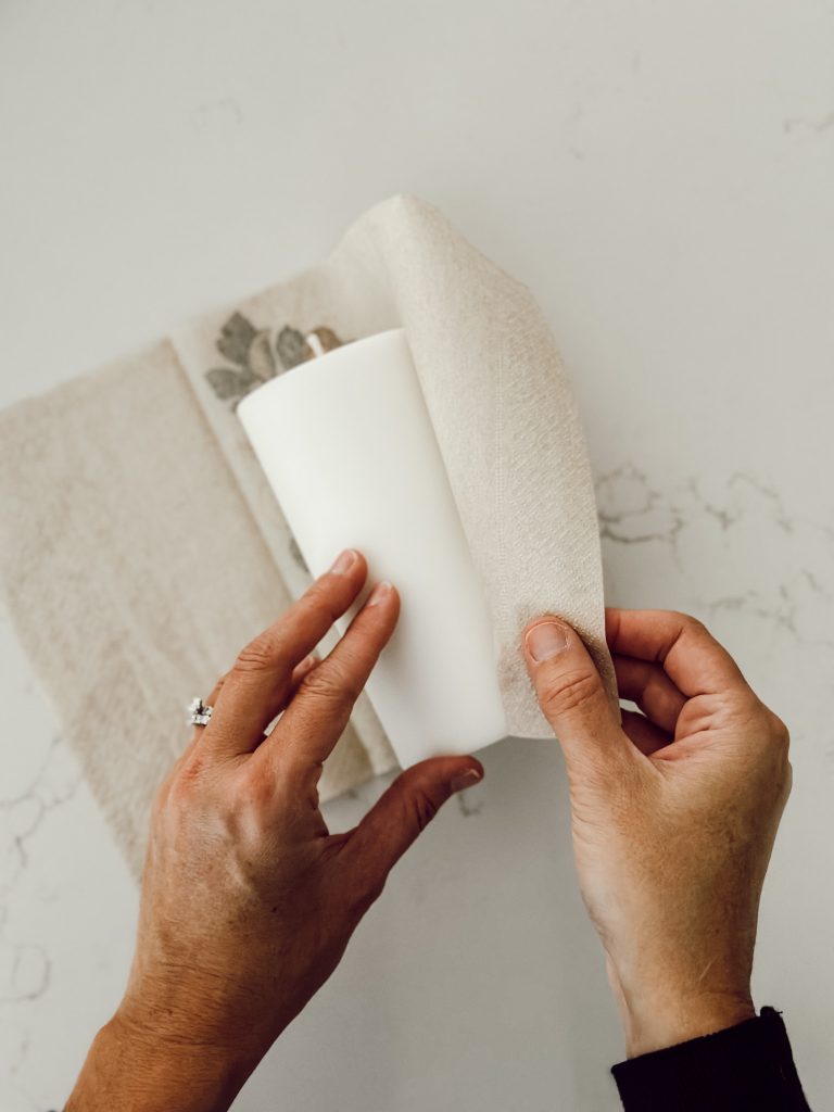 Wrap the paper napkin around the pillar candle to determine how much you need to trim off the napkin.