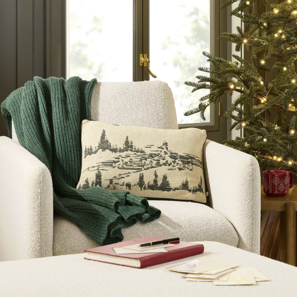 Hearth and Hand 2025 Christmas collection at Target featuring a white chair with a green chunky knit blanket and a Christmas throw pillow.
