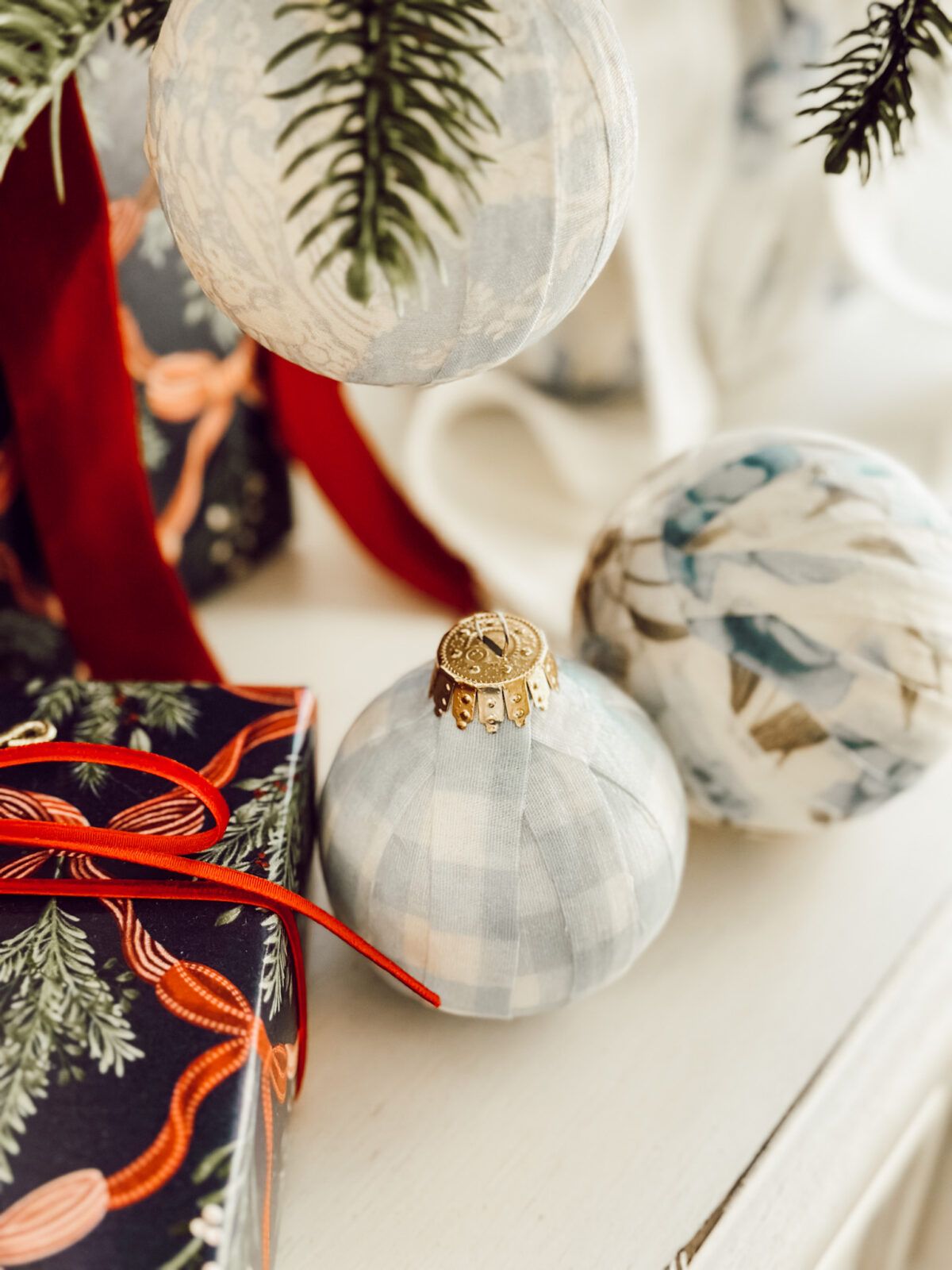 DIY decoupage fabric ornaments with Mod Podge on night stand with wrapped Christmas presents.