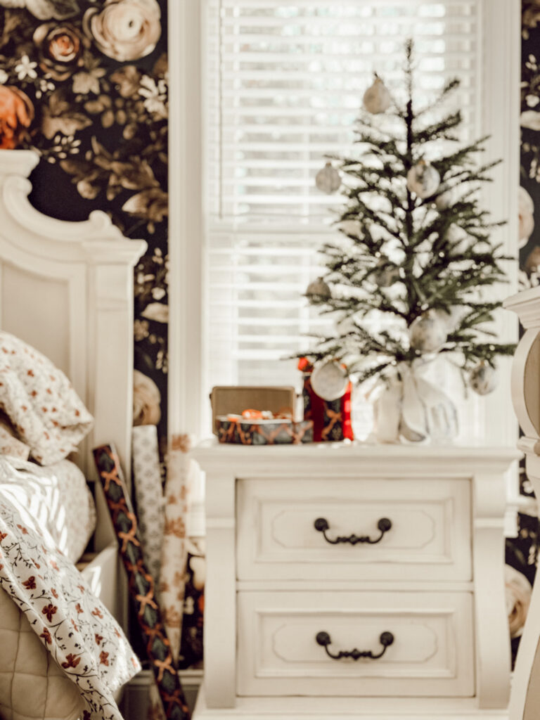 DIY ornaments hanging on a Christmas tree in bedroom with floral accents.