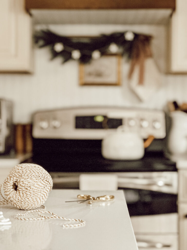 Holiday crafting on the kitchen island with a roll of twine and scissors to make easy Christmas DIYs.