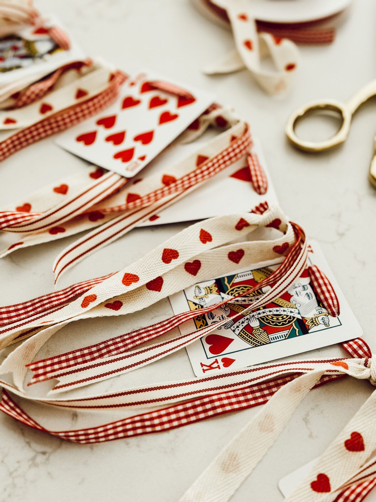 DIY valentine heart playing card garland with ribbon for easy Valentine's Day decor.