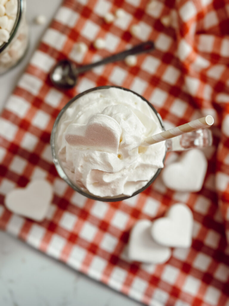 White hot chocolate with whipped cream and a heart shaped marshmallow for an easy Valentine treat.