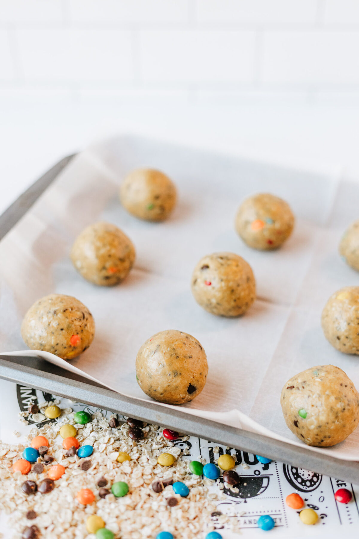Cookie dough balls on parchment paper lined baking sheet.
