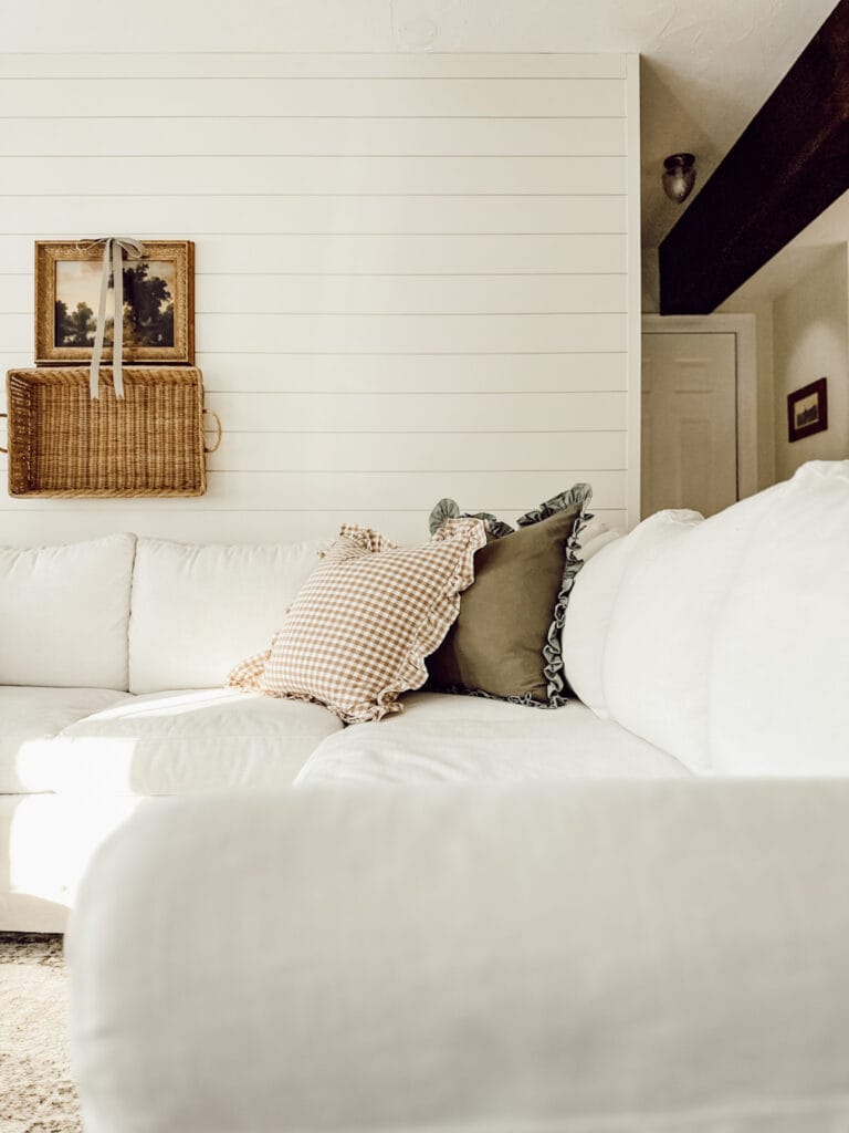 Mid-winter home edit in the living room with just a few throw pillows on the couch and framed art on the wall.