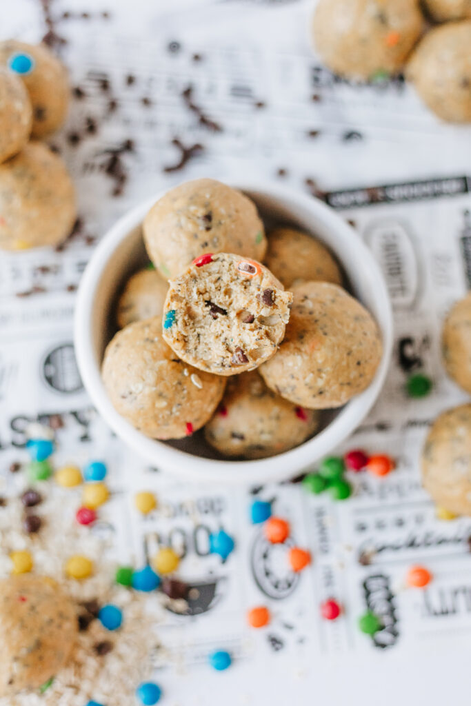 Monster cookie energy balls with protein powder, coated candies, mini chocolate chips, and peanut butter.