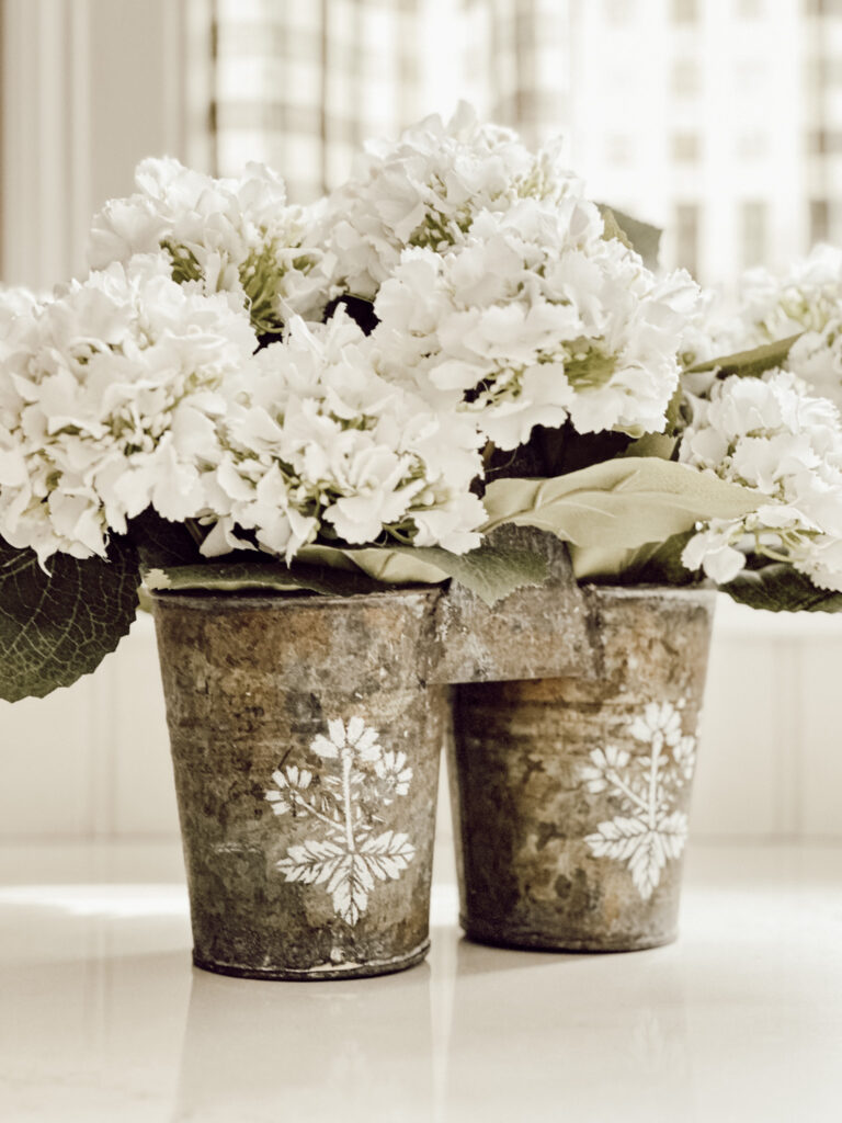 Vintage tin container filled with faux hydrangeas stenciled with a botanical stencil.