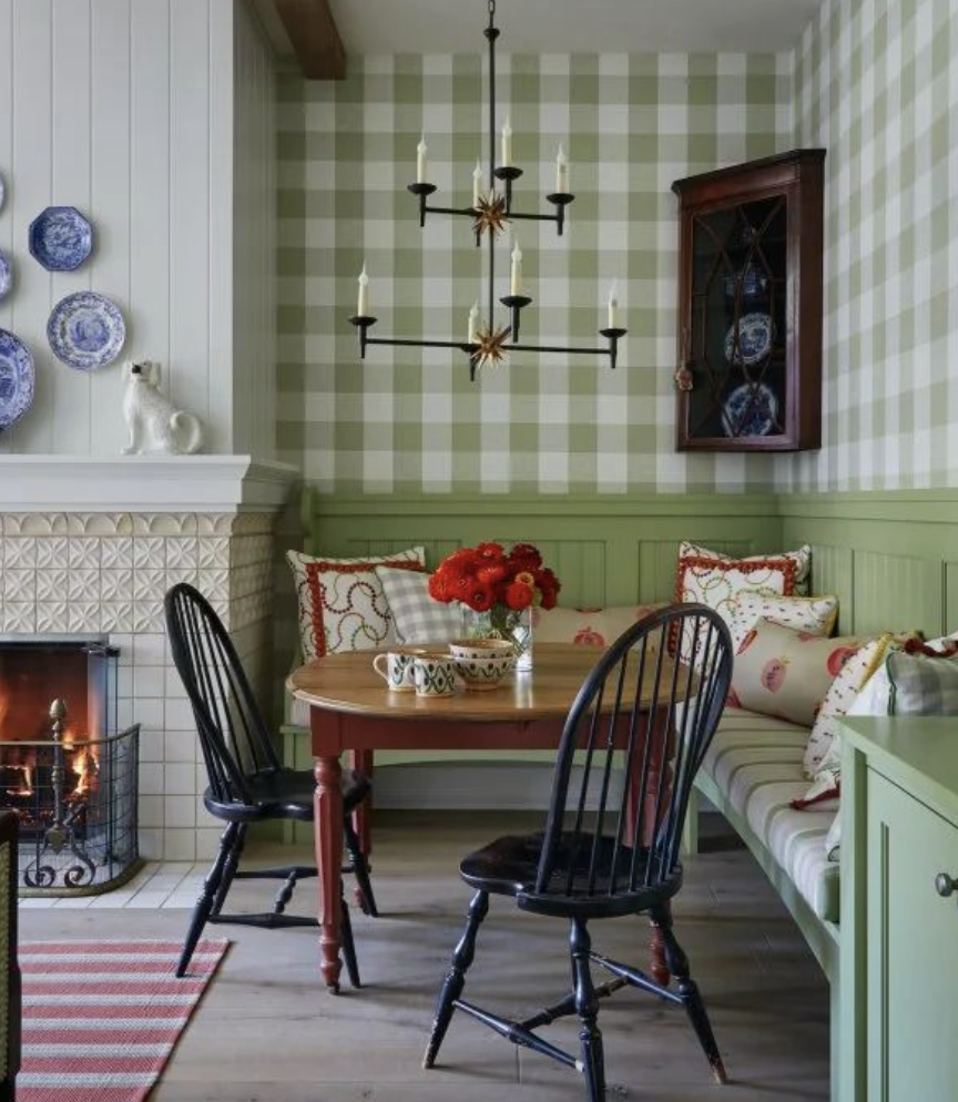 Green gingham wallpaper in a country cottage kitchen with a kitchen table and fireplace.