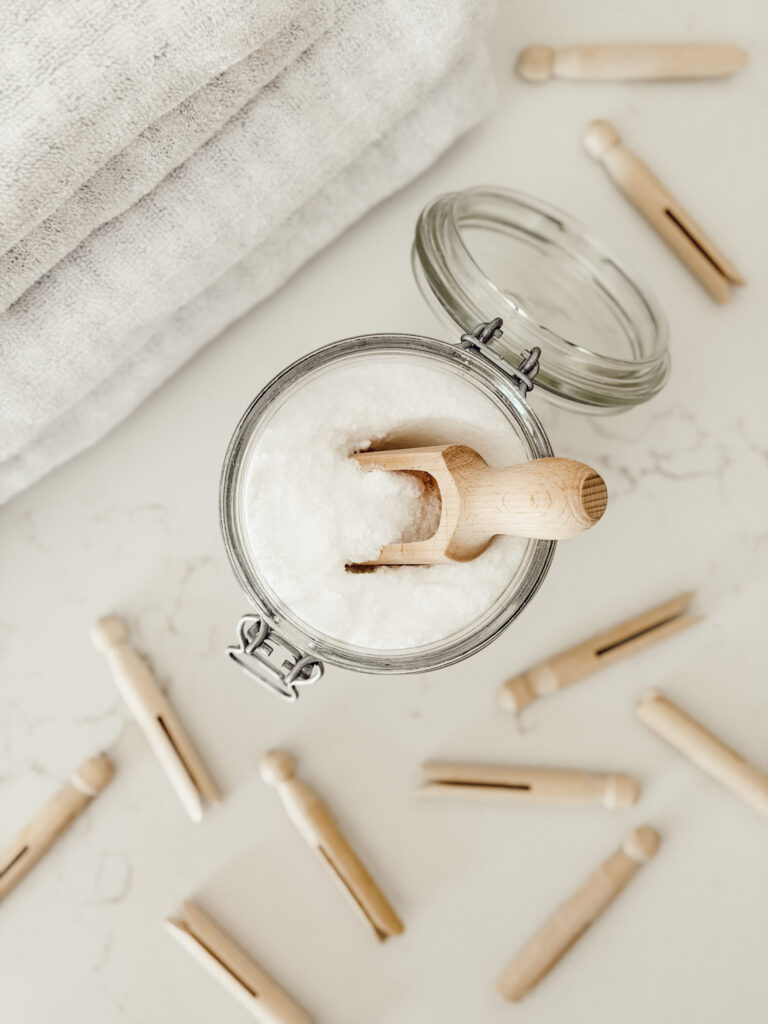 Scent booster DIY for laundry in a glass mason jar with a wooden scoop.