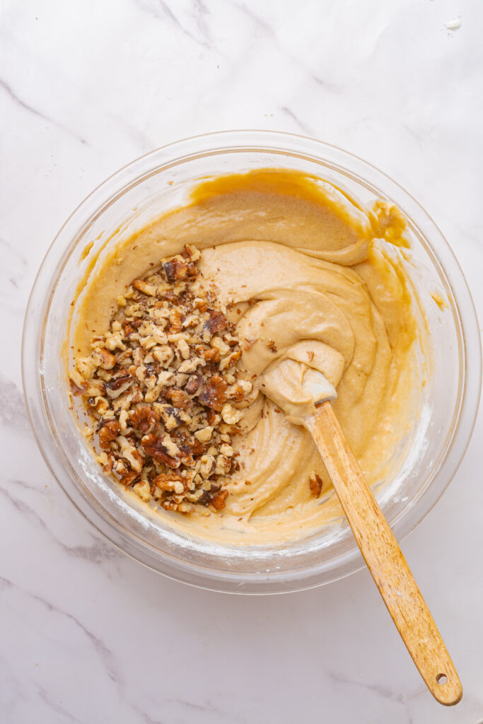 Chopped walnuts mixed into coffee cake batter in a mixing bowl.