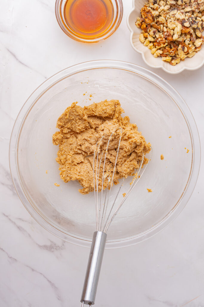 Coffee cake batter in a glass mixing bowl with a metal whisk.