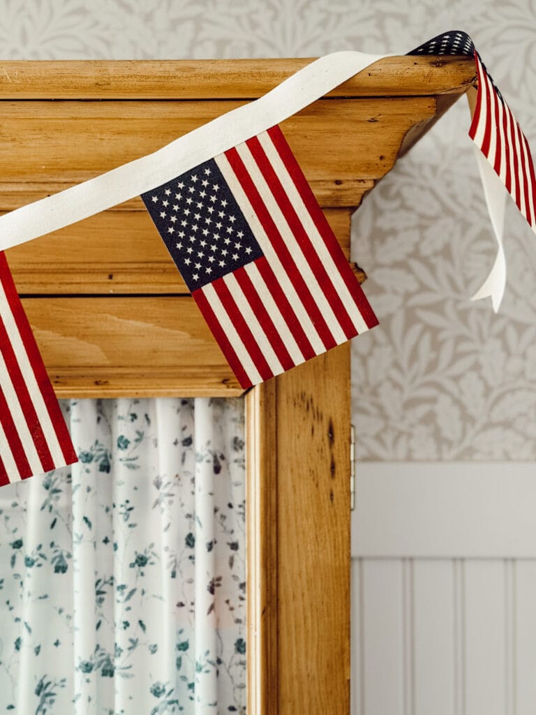Handmade American flag garland hanging on hutch for cozy summer decorations.