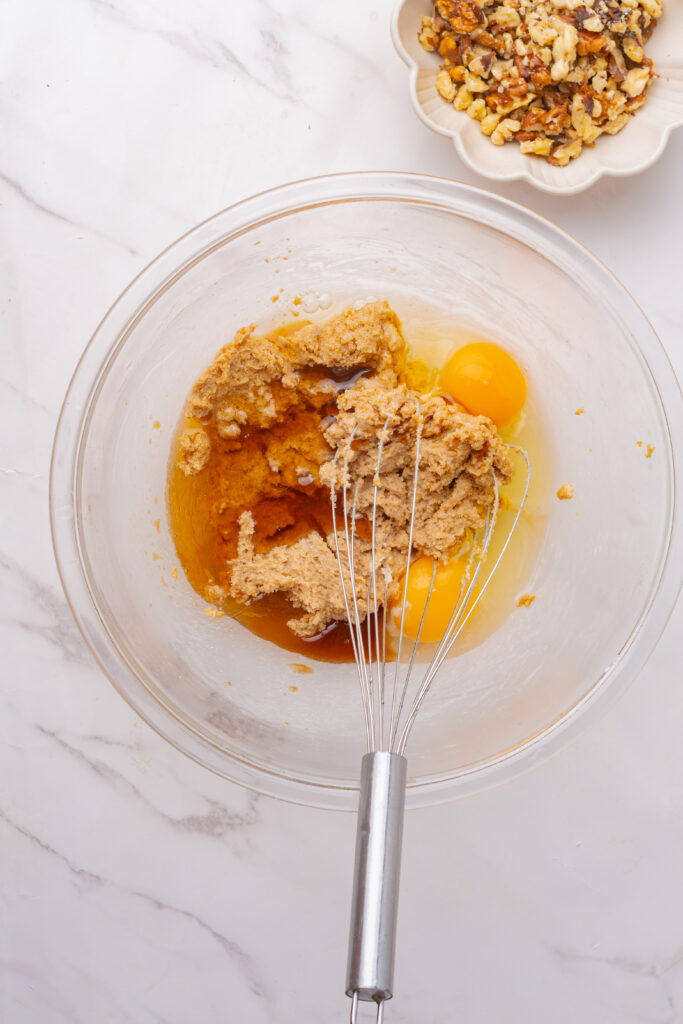 Large eggs whisked into brown sugar and butter in a large mixing bowl.