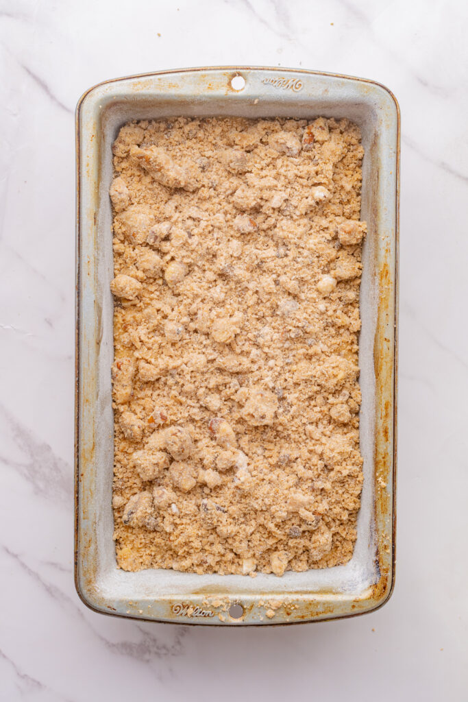 Sprinkled cinnamon streusel topping on coffee cake loaf.