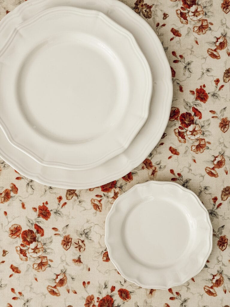 Budget-friendly ceramic plates to create a tiered stand on a red floral tablecloth.