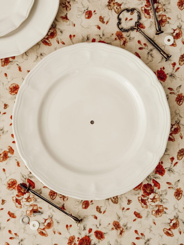 The bottom of the DIY tiered tray starts with a dinner plate with a hole drilled in the center.