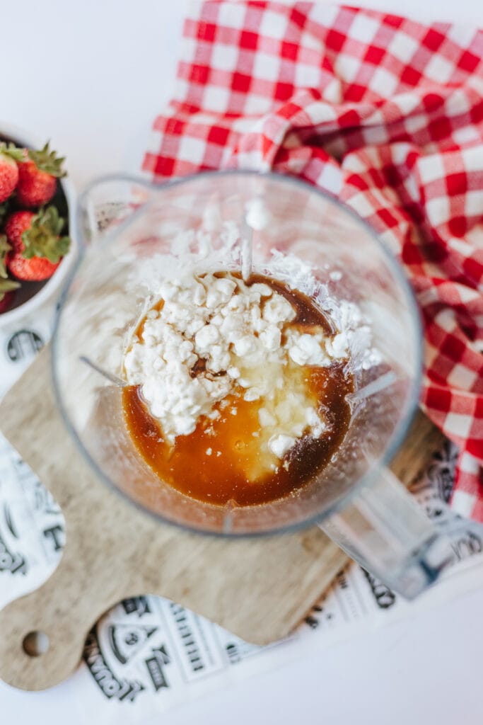 Adding cottage cheese, honey, and vanilla extract to a blinder to make high protein ice cream.