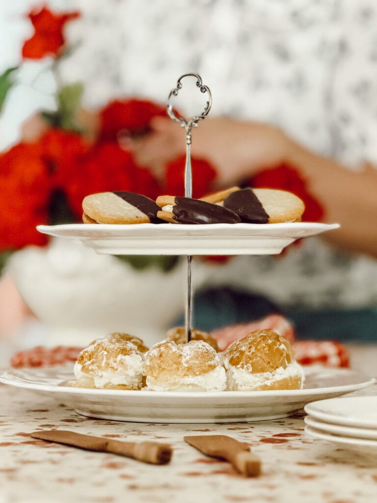 A DIY tiered tray with ceramic plates filled with cookies and cream puffs for entertaining.