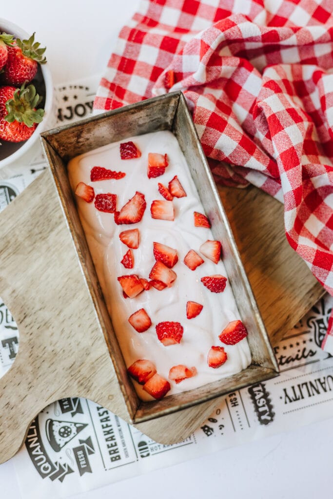 First layer of cottage cheese ice cream in a metal loaf pan topped with chopped berries.