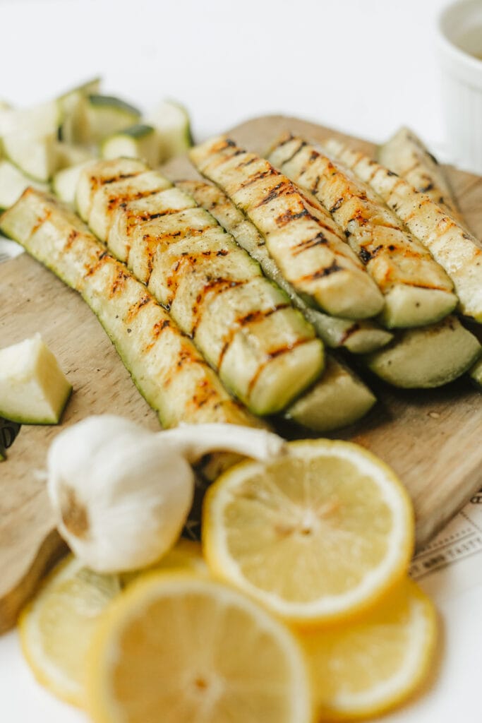 Garlic lemon marinated zucchini spears on a wooden cutting board.