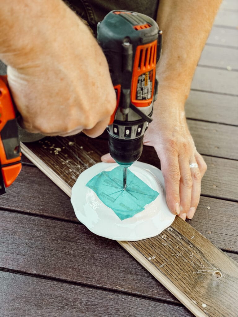To create a DIY tiered tray with ceramic plates, use a power drill to drill a small hole through the center of the plate.