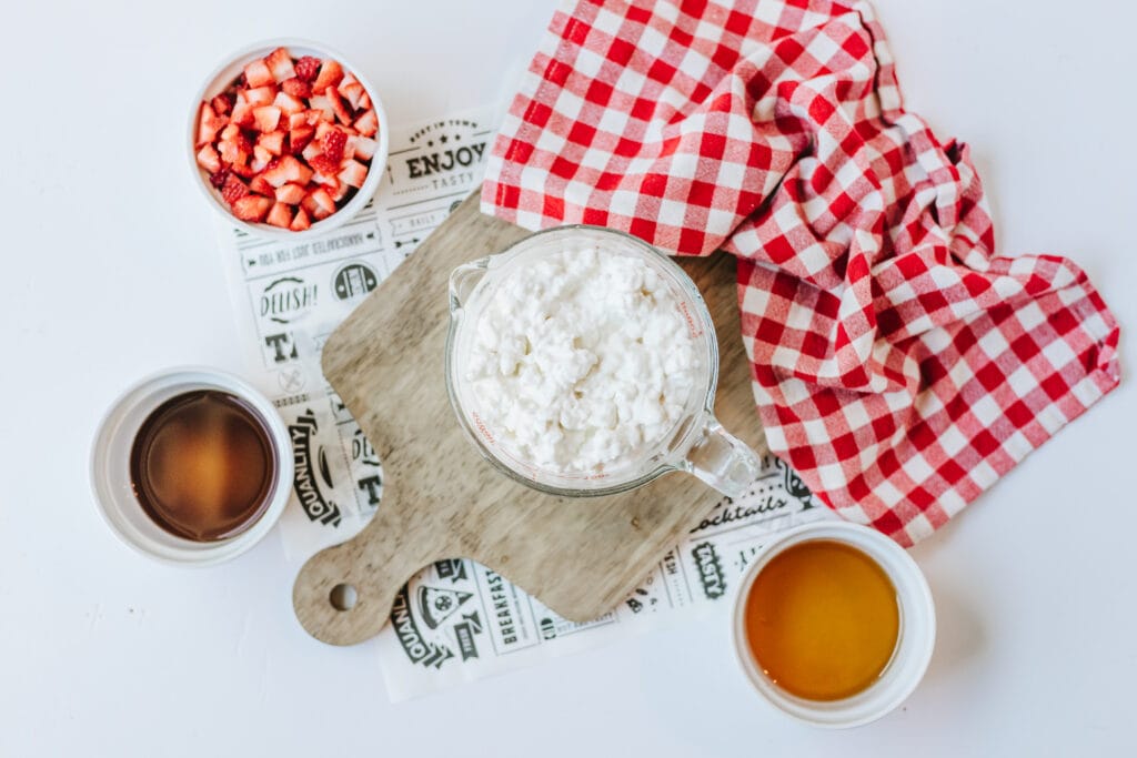 Simple ingredients for cottage cheese ice cream include cottage cheese, fresh strawberries, honey, and pure vanilla extract.