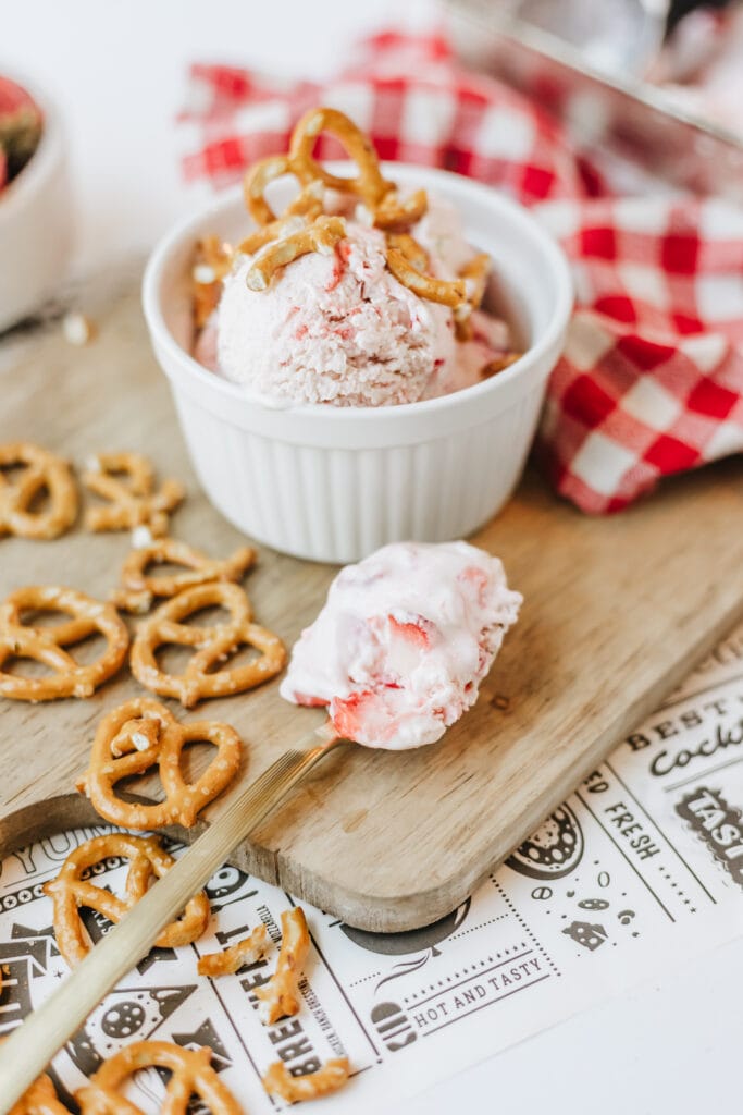 Spoonful of cottage cheese strawberry ice cream on a wooden board.