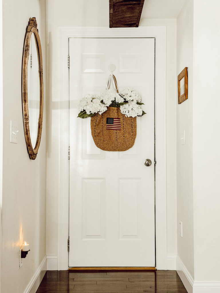 DIY summer decor with a rattan bag, hydrangeas, and ribbon hanging on a door.