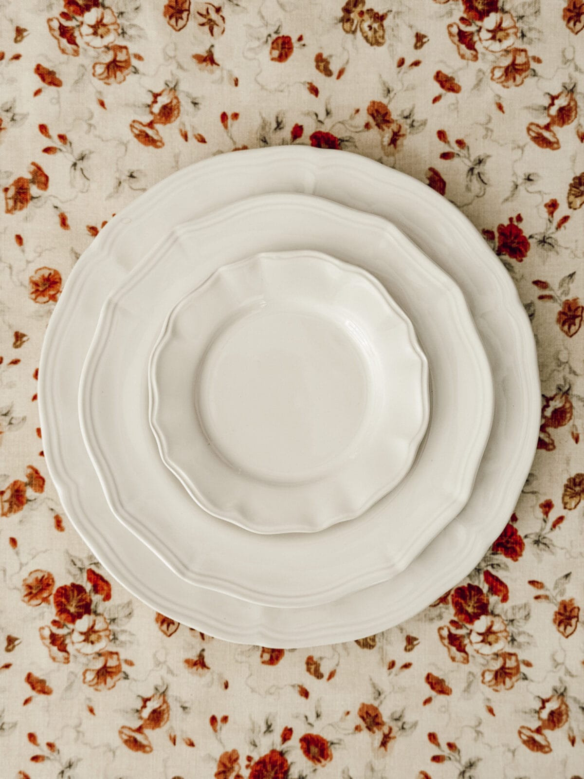 White ceramic plates on a floral tablecloth to show what kind of plates to use to make a DIY tiered stand.