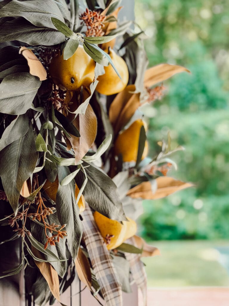 DIY fall decoration for your front door includes a fall wreath embellished with faux pears for fall.