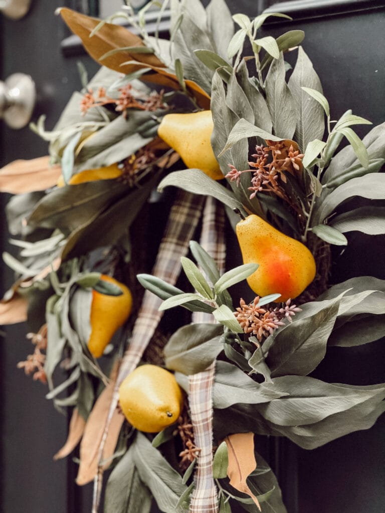 DIY faux pear wreath with a plaid ribbon hanging on the front door of our home.